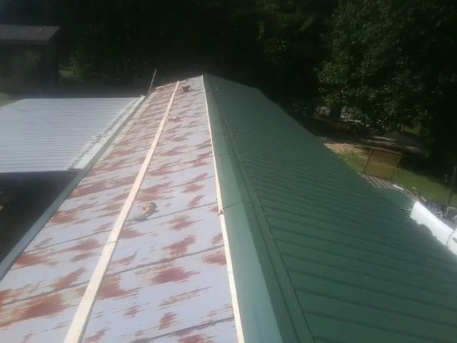 Old rusted panels beside newly installed green metal roofing — Wind Damage Roof Repair by Roofing Brothers in Browns Summit