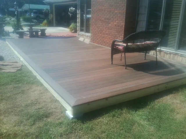 New wood deck and wicker chair beside a brick house in Browns Summit