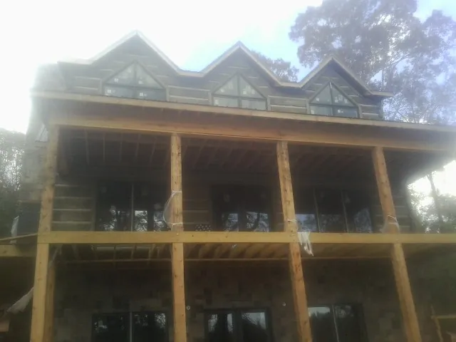 Dormers and porch framing on a large log home under construction — Roof Coating work by our crew in Browns Summit