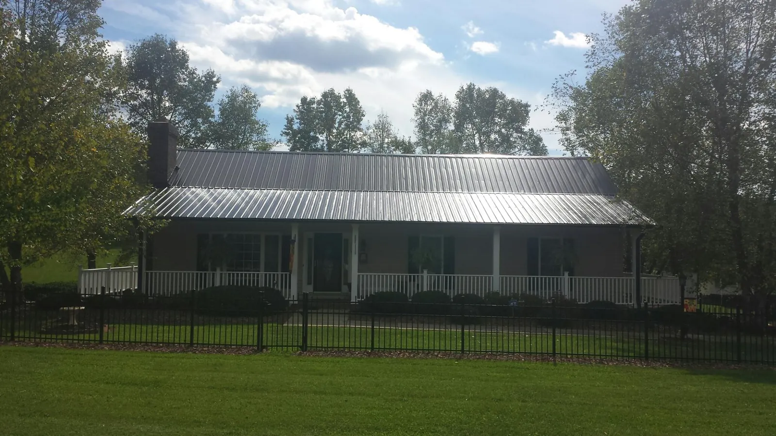 Gray metal roof on a brick ranch with a full width front porch — Gutter Guard Installation work by our crew in Browns Summit