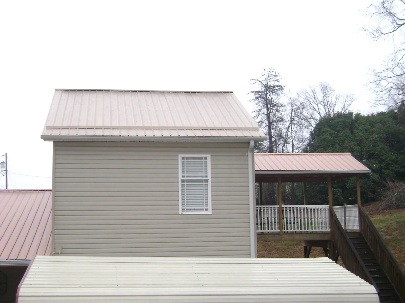 Tan metal roofs on a two story addition and attached porch, from a Roof Replacement job in Browns Summit