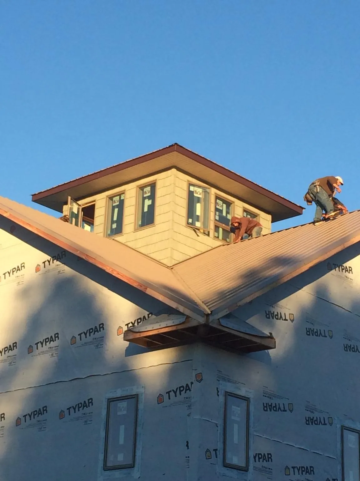 Roofers working around a rooftop cupola on a new metal roof at sunset — Roof Waterproofing in Browns Summit by Roofing Brothers